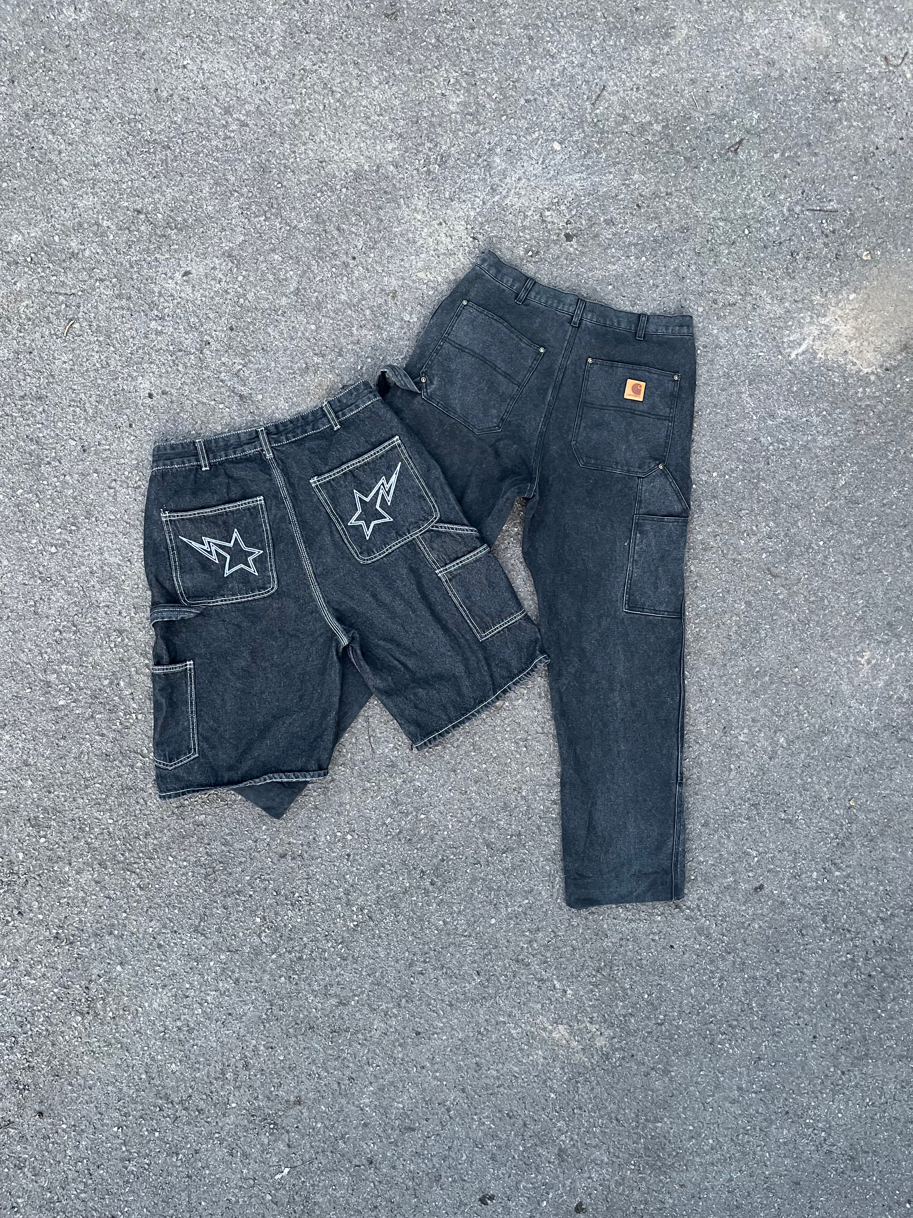 Pair of black jeans with star patches on a gray surface